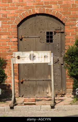 Holzstöcke auf dem Hof von Schloss Olsztyn, Polen. Mittelalterliches Strafgerät vor einer schweren Holztür mit eisernen Details. Stockfoto