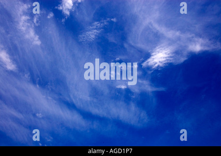 Weiße Wolkenfetzen vor einem tiefblauen Himmel Stockfoto
