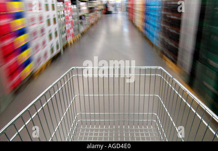 schieben einen leeren Wagen durch Gänge mit Stapeln von Getränke-Fällen im Supermarkt Stockfoto