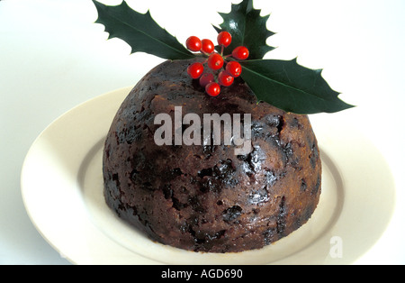 Christmas Pudding dekoriert mit Holly auf weißen Teller. Stockfoto