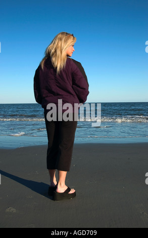 Junge Blonde Kaukasische Frau in lila Jacke Spaziergänge Jagd Insel Strand SC im Herbst USA Stockfoto