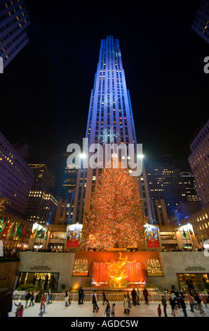 Skater am Rockefeller Center Ice Rink Weihnachtsbaum und projizierte Schneeflocken auf beleuchteten Gebäuden Stockfoto