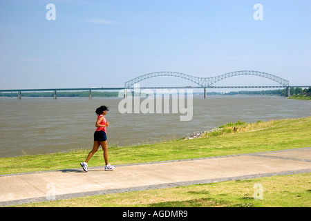 Frau Joggen entlang dem Mississippi Fluß Damm mit der Hernando Desoto Memorial Bridge im Hintergrund in Memphis, Tennessee Stockfoto