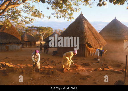 Kleines Dorf mit Frauen und Hütten bei Sonnenaufgang in Simbabwe Afrika Stockfoto