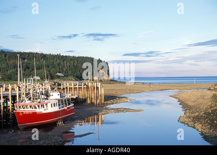 Ebbe an Alma New Brunswick mit roten Fischerboot im Schlamm unter dem Dock sitzen Stockfoto