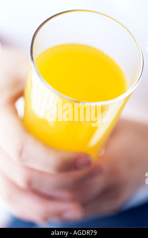 NAHAUFNAHME VON HÄNDEN MIT EINEM GLAS ORANGE Stockfoto