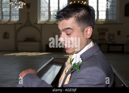 Kurdische Bräutigam prüft seine Uhr, wie er in der englischen Kirche für Braut Ankunft wartet Stockfoto