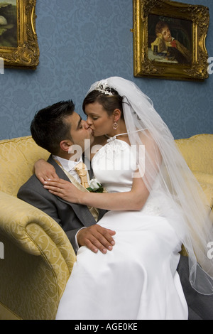 Frisch verheiratete Kuss auf der Couch in ihren Flitterwochen-Anzug Stockfoto