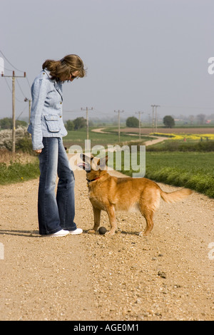 Frau steht mit ihrem elsässischen Hund auf Land Track in Cambridgeshire Landschaft schlängelt. Stockfoto