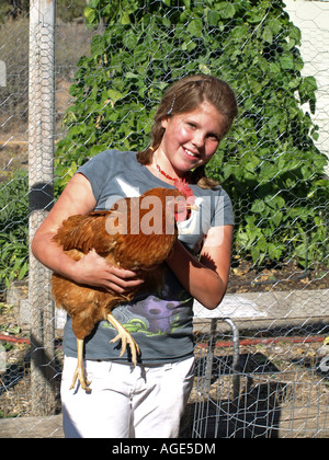 Eine 12-jährige Bauernmädchen in Zöpfen kuschelt ihr Buff Orpington Huhn in einem Hühnerstall im September Stockfoto