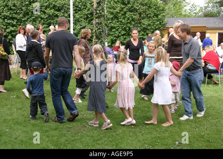 Familien, die Spaß am feiern Mittsommer in Schweden. Maibaum tanzen und spielen um den Mittsommer-Pol Stockfoto