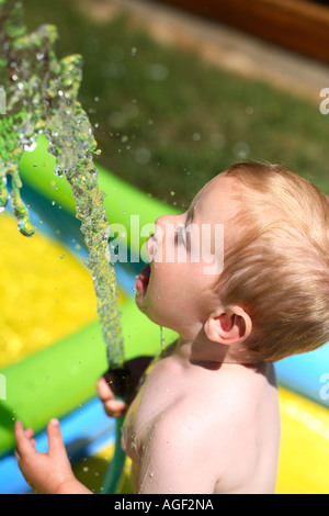 Zwei Jahre alter Junge trinkt aus Schlauch Stockfoto