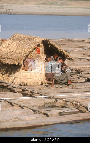 "FLOß" transportieren wertvolle Teakholz-Protokolle auf dem Irrawaddy Fluss, Burma (Myanmar) hat einfach strohgedeckten Wohnräume Stockfoto