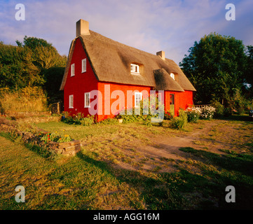 ein rot bemalten Ferienhaus mit Reetdach in einer ländlichen Umgebung Stockfoto