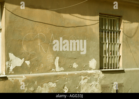 Graffiti, Schatten, ein vergittertes Fenster und peeling Gips auf eine alte Hauswand in Krakau, Polen Stockfoto