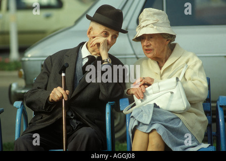 Flüsternde Senioren Ehemann flüstert Gespräch. Die Hand bedeckt den Mund. Klug gekleidetes altes Paar in Cannes Südfrankreich 1980er 1980 Stockfoto