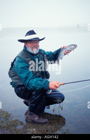 Fliegenfischer mit einer Regenbogenforelle gefangen und freigegeben von einem kleinen See in Montana in der Nähe von Red Lodge Stockfoto