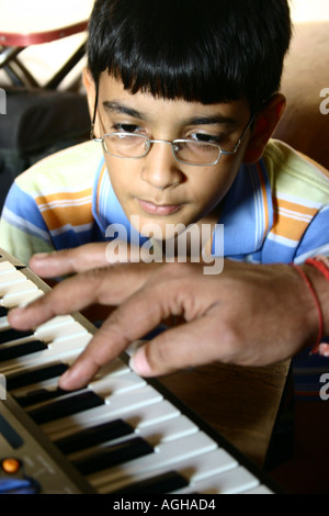 RSC91157 Hand von einem indischen Mann Vater spielt Klavier und ein zwölf Jahre alte indische Teen Teenager junge lernen beobachten attentivel Stockfoto
