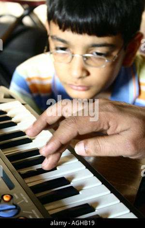 RSC91139 Hand eines indischen Mannes, spielt Klavier und ein zwölf Jahre alten indischen Jungen lernen beobachten aufmerksam Bombay jetzt Mumb Stockfoto
