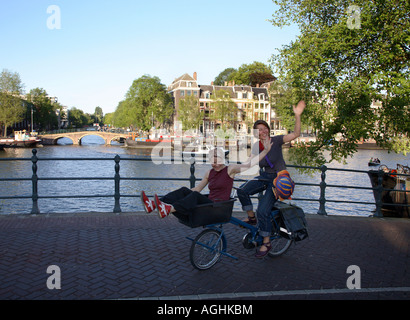 Zwei Frauen auf einem Fahrrad fahren entlang der Amstel, Amsterdam, Niederlande Stockfoto