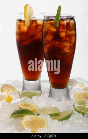 Eine Coca Cola gegossen in zwei Gläser mit Eiswürfeln schneiden Zitrone Limette Cola Getränk weiß Tisch Hintergrund Marke Getränke Softdrink in den USA Hi-res Stockfoto