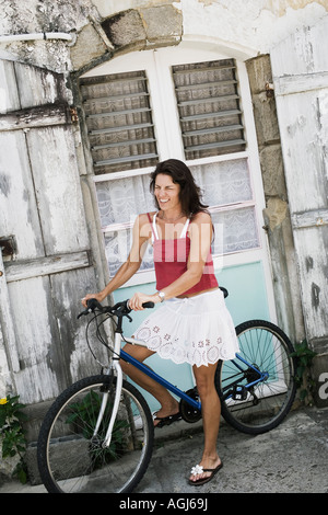 Mitte Erwachsene Frau lernen, wie man ein Fahrrad vor einem Haus Stockfoto