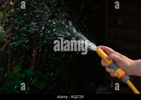 Hand mit einem Gartenschlauch. Stockfoto