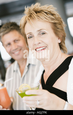 Porträt einer reifen Frau, die mit einem Glas cocktail mit einem älteren Mann neben ihr Stockfoto