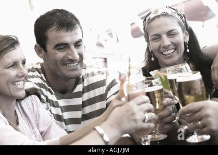 Mitte erwachsenen Mann und zwei Frauen Toasten mit Biergläsern und lächelnd Stockfoto