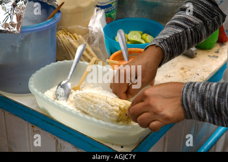 Weibliche Hispanic Straße Verkäufer (Alter 31) zu geröstetem Mais mit Käse Stockfoto