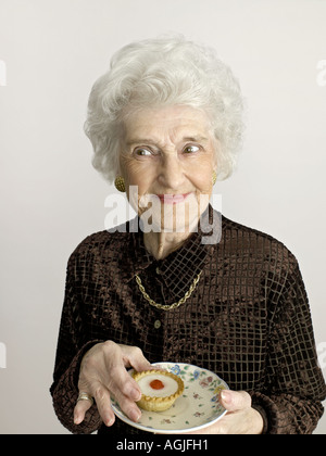 Ältere Frau mit Kirsche Bakewell tart Stockfoto