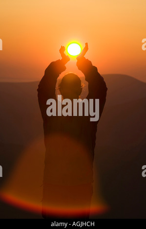 Eine Frau mit der untergehenden Sonne auf großen Torfgebieten, Lake District, Großbritannien Stockfoto