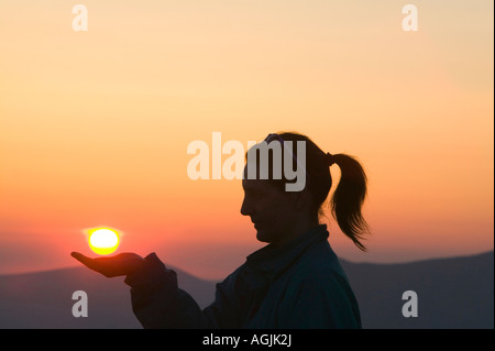 Eine Frau mit der untergehenden Sonne in der Seenplatte, Cumbria, UK Stockfoto