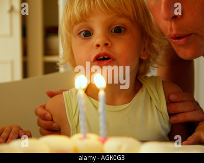 Kleines Mädchen bläst zwei brennende Kerzen an ihrem zweiten Geburtstag, was ihr Name Irene ist Stockfoto