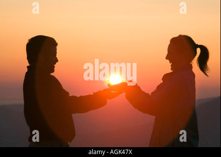 Ein paar halten die untergehende Sonne in den Lake District, Cumbria, UK Stockfoto