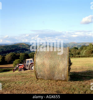 Großer Ballen auf einem Feld in Kunststoffverpackung, Traktor und Landschaft Blick auf die Landschaft auf einem walisischen Bauernhof in Carmarthenshire Wales Großbritannien KATHY DEWITT Stockfoto