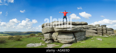 Junger Mann mit ausgestreckten Armen auf einem Felsen stehend Stockfoto