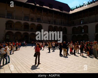 Sonnenverwöhnten Menschenmassen vor der Bögen und Säulen im Hof des Königs auf dem Gelände von Schloss Wawel in Krakau, Polen. Stockfoto