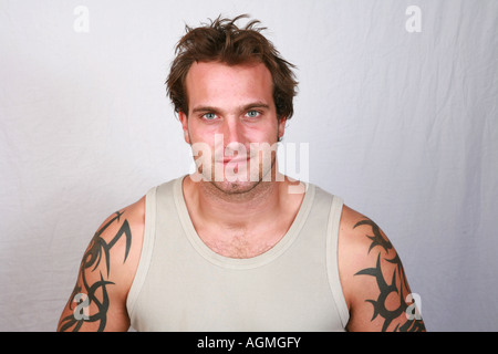 Young baute auch attraktive 20er Jahre Männlich mit Weste und schwere Arm Tattoos und neutralen Gesichtsausdruck Kopf und Schultern Porträt Stockfoto