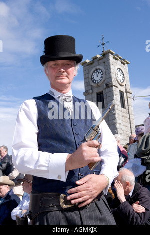 Schottische Veranstaltungen Creetown Country Music Festival Cowboy posiert mit Gewehr auf dem Platz mit Clocktower hinter Galloway Scotland UK Stockfoto