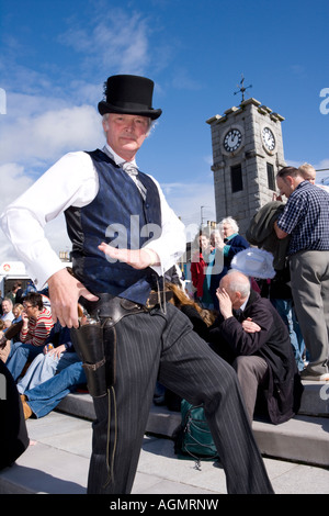 Schottische Veranstaltungen Creetown Country Music Festival Cowboy posiert mit Gewehr auf dem Platz mit Clocktower hinter Galloway Scotland UK Stockfoto