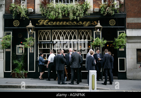 Büroangestellte und Geschäftsleute, trinken und Rauchen vor einem Pub in der Stadt am Mittag, London, England, UK Stockfoto