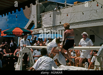 Deckspiele - ein Kissenkampf zwischen zwei weiblichen Passagieren auf dem Deck eines Kreuzfahrtschiffs TSS Maasdam der Holland America Line Mitte der 1950er Jahre. Stockfoto