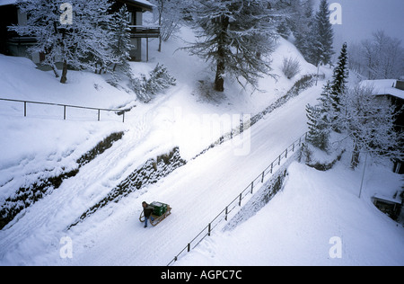 Schweiz, Mürren im Berner Oberland. Autofreie Skigebiet. Schleppen Gepäck zum Bahnhof auf hohe Straße © Brian Harris Stockfoto