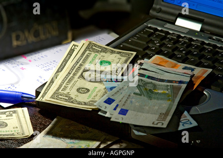 US-Dollar und Euro-Banknoten auf einem Notebook-Computer, ein Weißbuch mit handschriftlichen Berechnungen Stockfoto