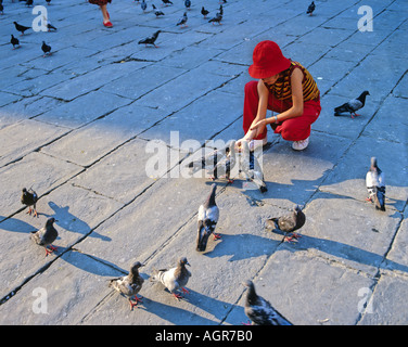 Ein Mädchen, das Füttern von Tauben in Venedig von San Marco Square Stockfoto