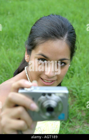 Porträt einer lächelnden jungen Frau, die mit einer digitalen Kamera nachschlagen Stockfoto