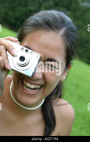 Porträt einer lächelnden jungen Frau, die mit einer digitalen Kamera nachschlagen Stockfoto