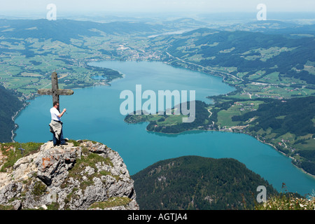 Ein Mann steht am Holzkreuz auf dem Schafberg mit Blick auf den Mondsee. Salzkammergut, Österreich. Stockfoto