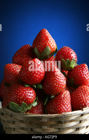 SSK79549 Frucht rote Erdbeeren in einem Korb vor dem blauen und schwarzen Hintergrund Stockfoto